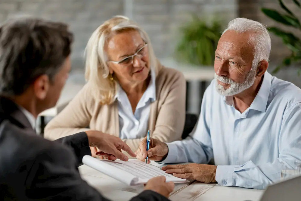 Senior couple meeting with financial advisor to review and sign retirement documents