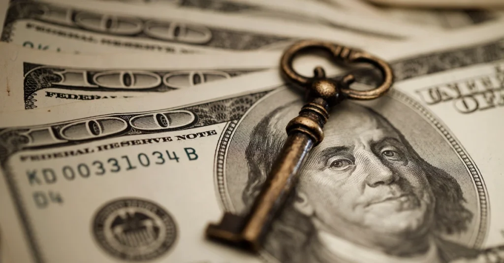 Close-up of antique key placed on top of U.S. $100 bills, symbolizing financial security, inheritance, and the concept of building generational wealth.