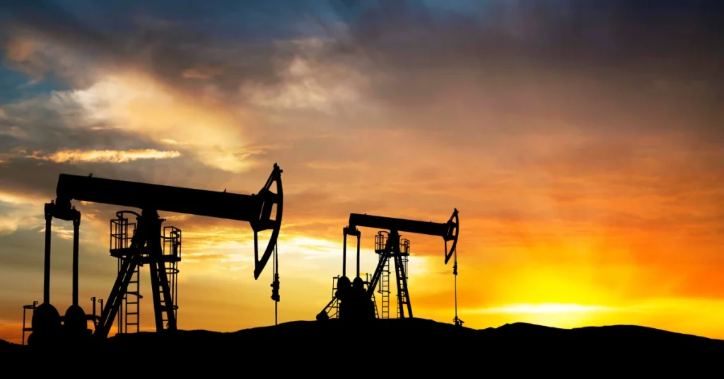 Silhouettes of oil pumpjacks extracting crude oil from the ground at sunset, symbolizing petroleum production and energy industry operations.